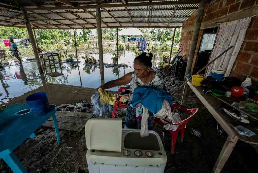 Mangsa banjir sedang menyelamatkan barangan rumah ketika kediaman mereka dinaiki air banjir di utara Colombia. AFP