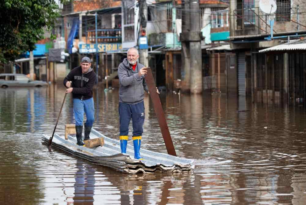 Dua lelaki mendayung rakit diperbuat daripada atap zink dan styrofoam sedang menyusuri jalan dinaiki air di Porto Alegre, Brazil. AFP