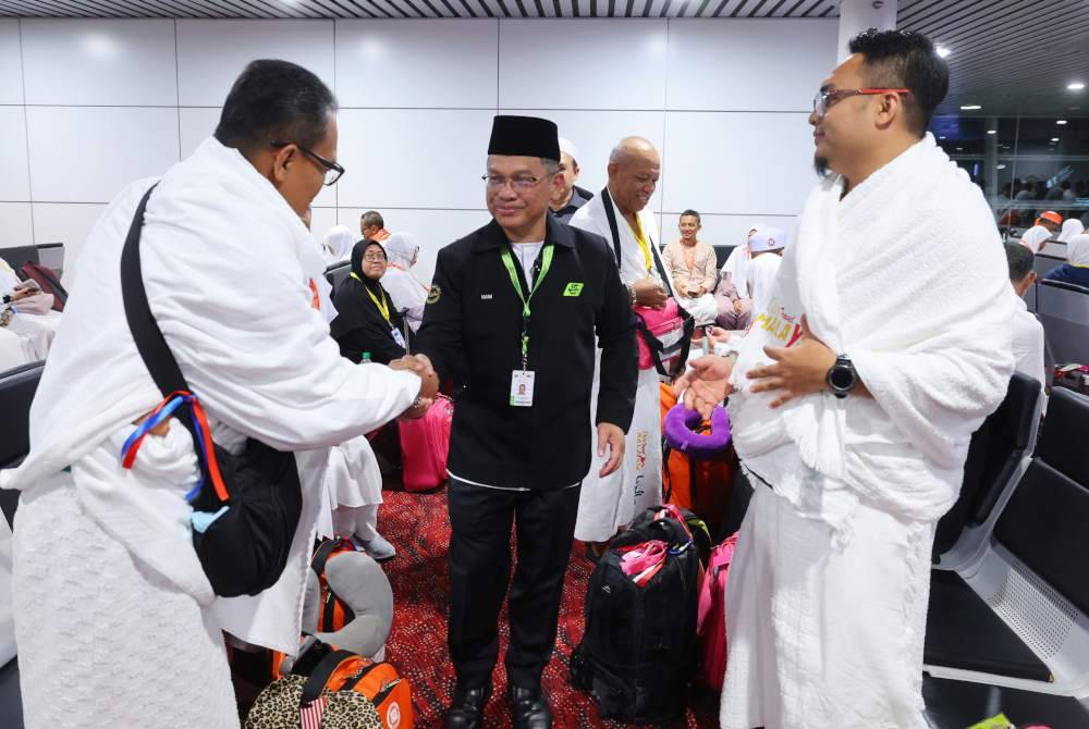 Menteri di Jabatan Perdana Menteri (Hal Ehwal Agama) Datuk Dr Mohd Na'im Mokhtar (tengah) menyantuni bakal-bakal jemaah haji sebelum berlepas untuk menunaikan haji di Lapangan Terbang Antarabangsa Kuala Lumpur (Terminal 1) tengah malam semalam. Foto Bernama