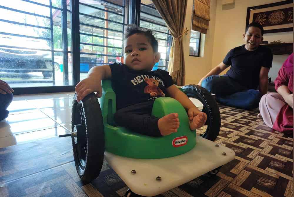 Qhalish duduk di atas kerusi roda ciptaan ayahnya.