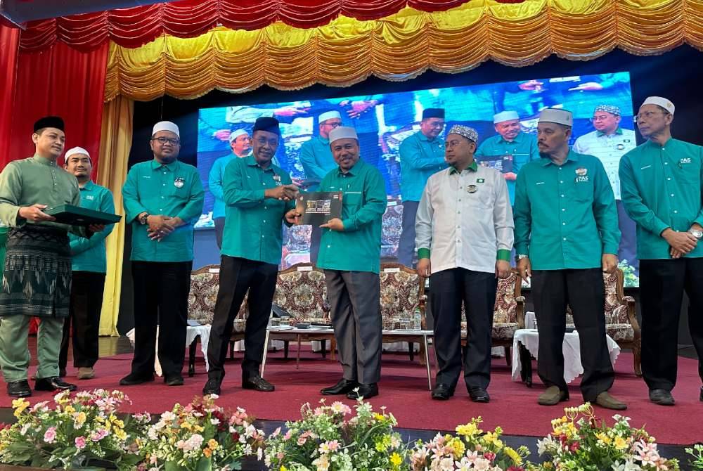 Takiyuddin (tiga dari kiri) menyampaikan buku Kota Bharu kepada Ahmad (tengah) sebagai simbolik perasmian mesyuarat.