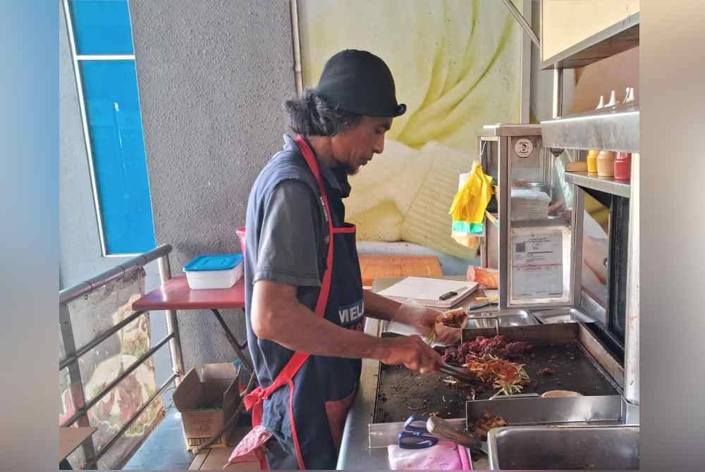 Yusaimi menyediakan inti kebab yang ditempah pelanggan di gerainya yang beroperasi di Bandar Chukai, Kemaman.