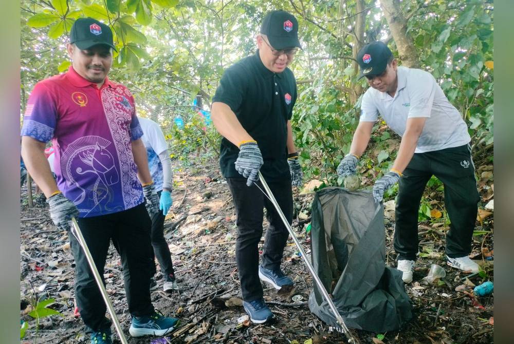 Tian Soon ( tengah) mengutip sampah di kawasan pesisir Sungai Skudai di Kampung Bakar Batu, Perling pada Ahad.