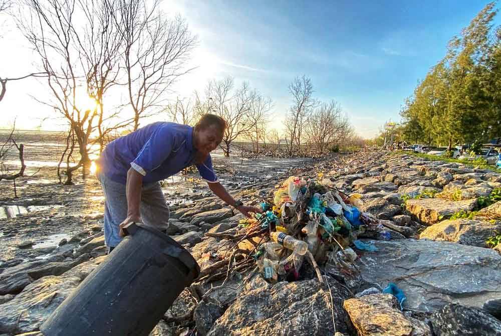 Alias sedang membersihkan kawasan persisiran Pulau Ketam untuk memastikan persekitaran terjaga.