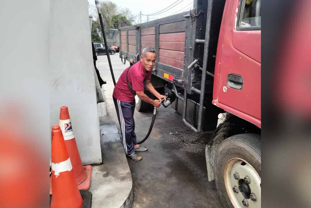 Zulkafli memenuhkan tangki lorinya di sebuah stesen minyak di Rantau Panjang