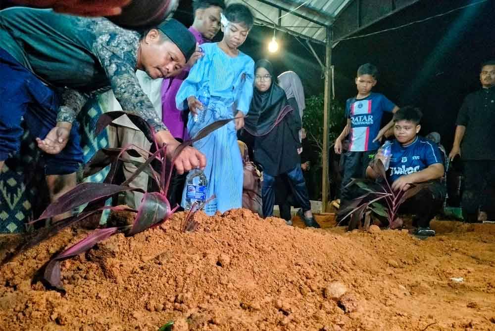 Mohd Farouq ketika mahu menjirus air di pusara arwah ibunya di Tanah Perkuburan Islam Tangki Air Ramuan China Besar, di sini, pada malam Ahad.