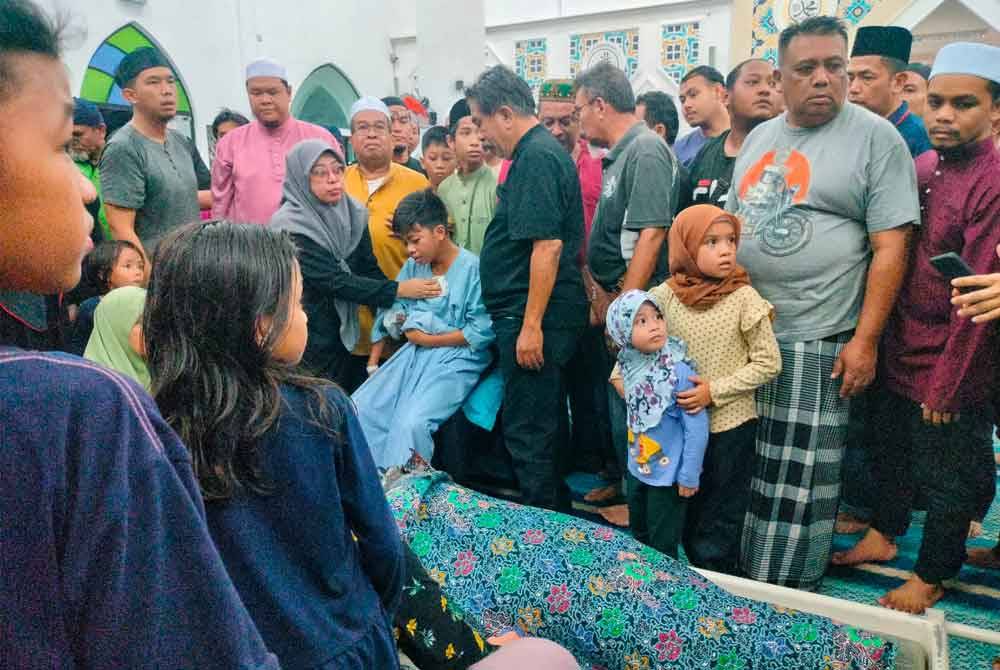 Mohd Farouq ditenangkan ahli keluarganya selepas mencium jenazah arwah ibunya di Tanah Perkuburan Islam Tangki Air Ramuan China Besar, di sini, pada malam Ahad.