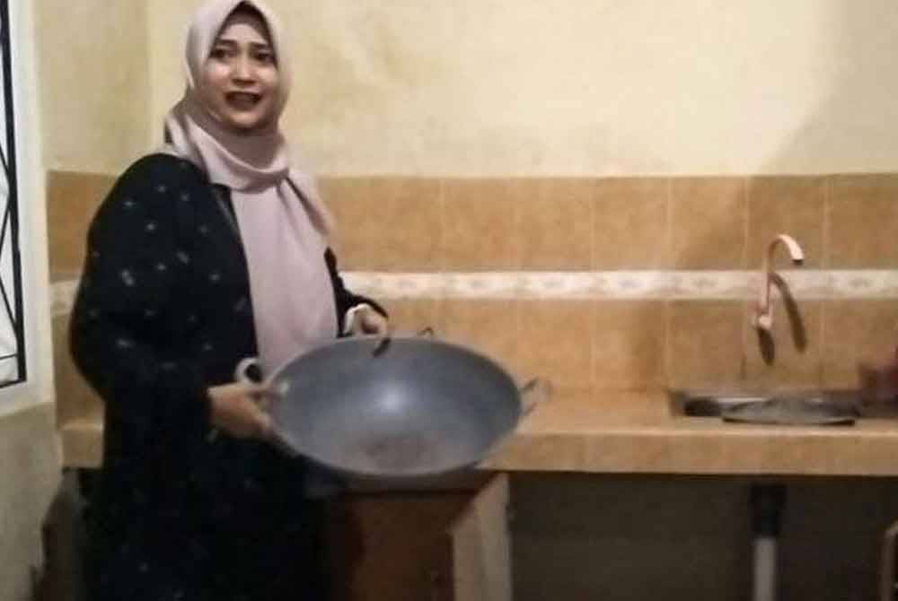 Rini menunjukkan kuali yang digunakan pencuri untuk menyembunyikan diri ketika cuba bersembunyi di rumah ibunya.- Agensi