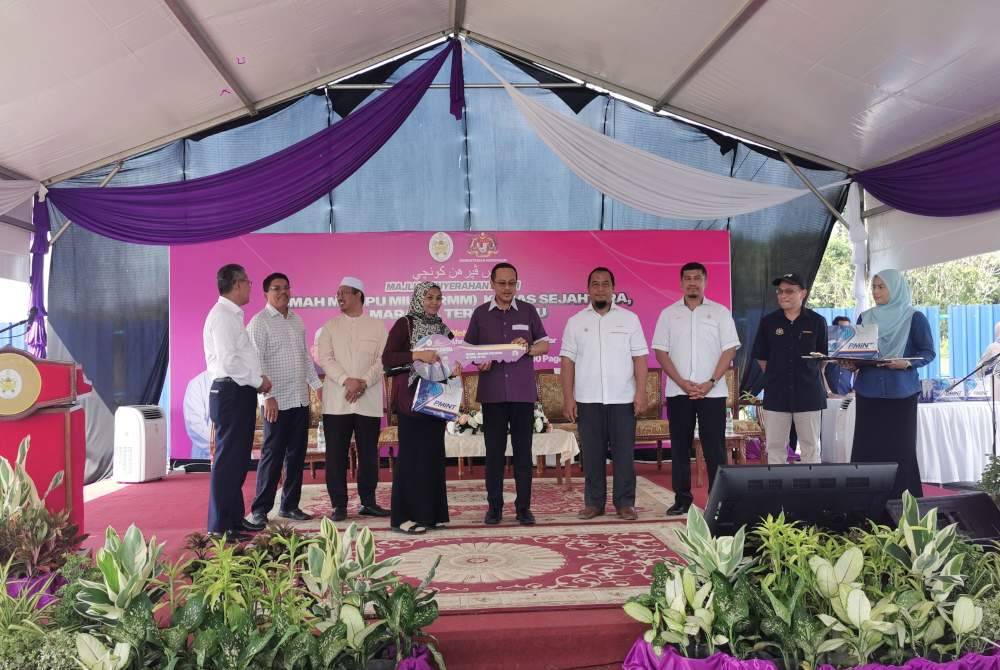 Ahmad Samsuri (tengah) menyerahkan kunci RMM Kemas Sejahtera kepada seorang penerima sempena majlis penyerahan kunci pada Isnin.