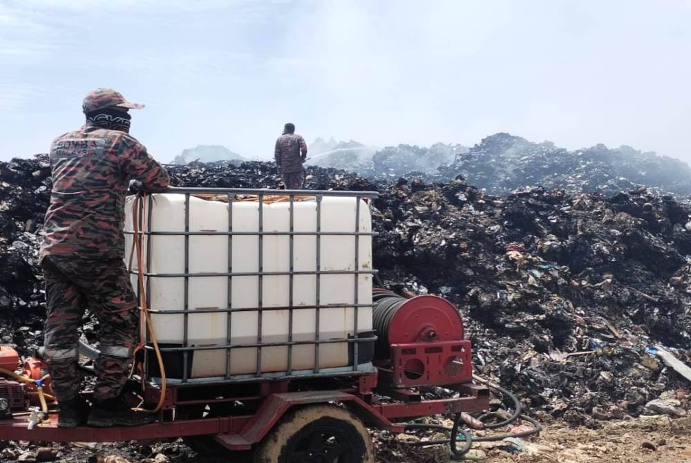 Anggota bomba berusaha memadamkan kebakaran tapak pelupusan sampah di Kampung Paya Rawa, di Besut.