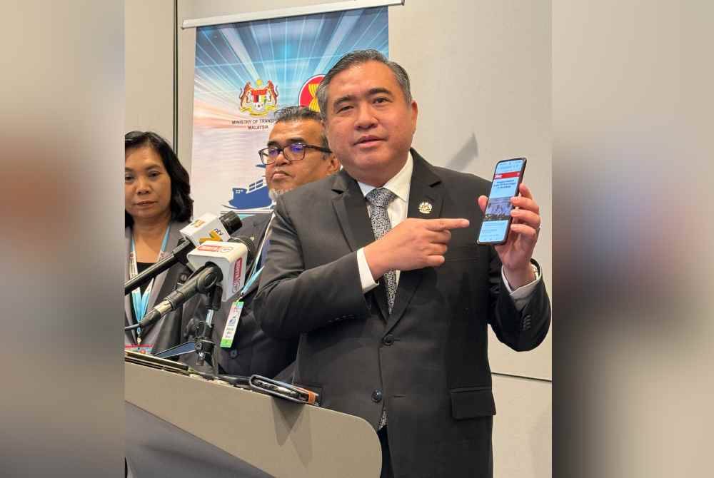 Anthony menunjukkan laporan berita mengenai Projek RTS ketika sidang akhbar di George Town pada Selasa.