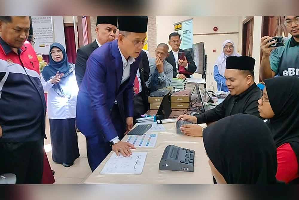 Mohd Fared (tengah) bertanya khabar pelajar berkeperluan khas penglihatan yang mencuba braille elektronik di Maktab Sultan Abu Bakar Johor Bahru, pada Selasa.
