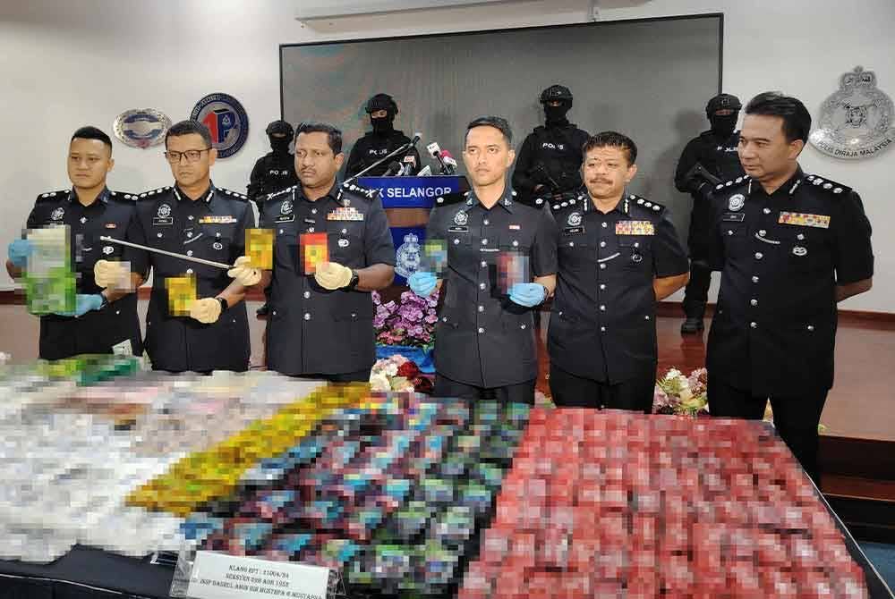 Hussein (tiga dari kiri) menunjukkan antara peket dadah yang dirampas dalam serbuan di Klang, 5 Jun lalu.