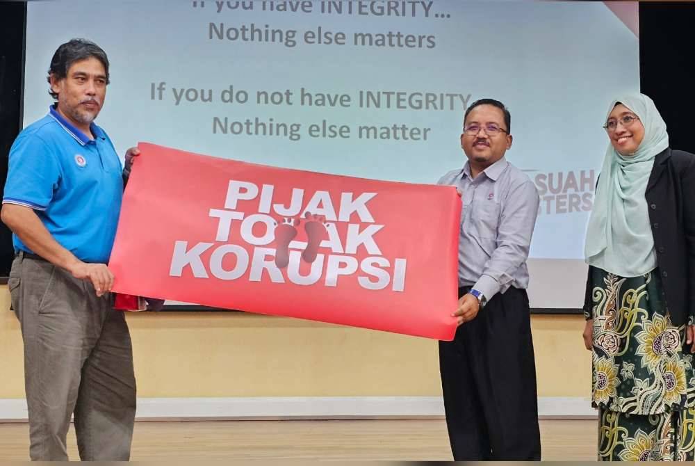 Ahmad Sofi (tengah) menyampaikan bunting kepada Hassan selepas berakhirnya sesi Jelajah Antirasuah di MRSM Parit pada Selasa.