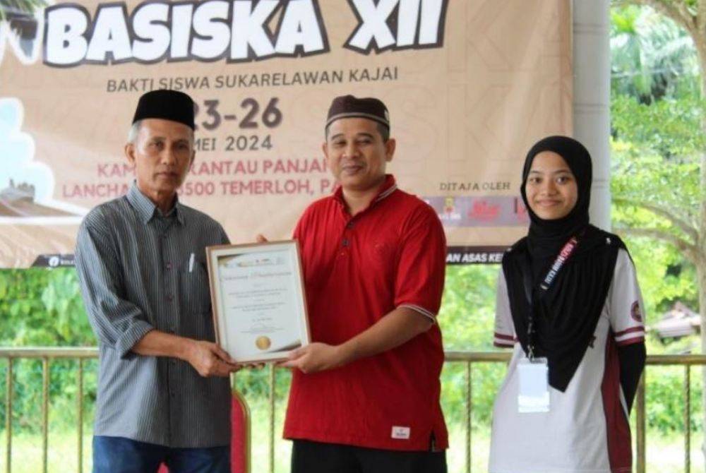 PROF MADYA DR ZAIZUL (tengah) menyerahkan sijil penghargaan kepada wakil penduduk Kampung Rantau Panjang, Temerloh selepas tamat program hujung Mei lalu. 