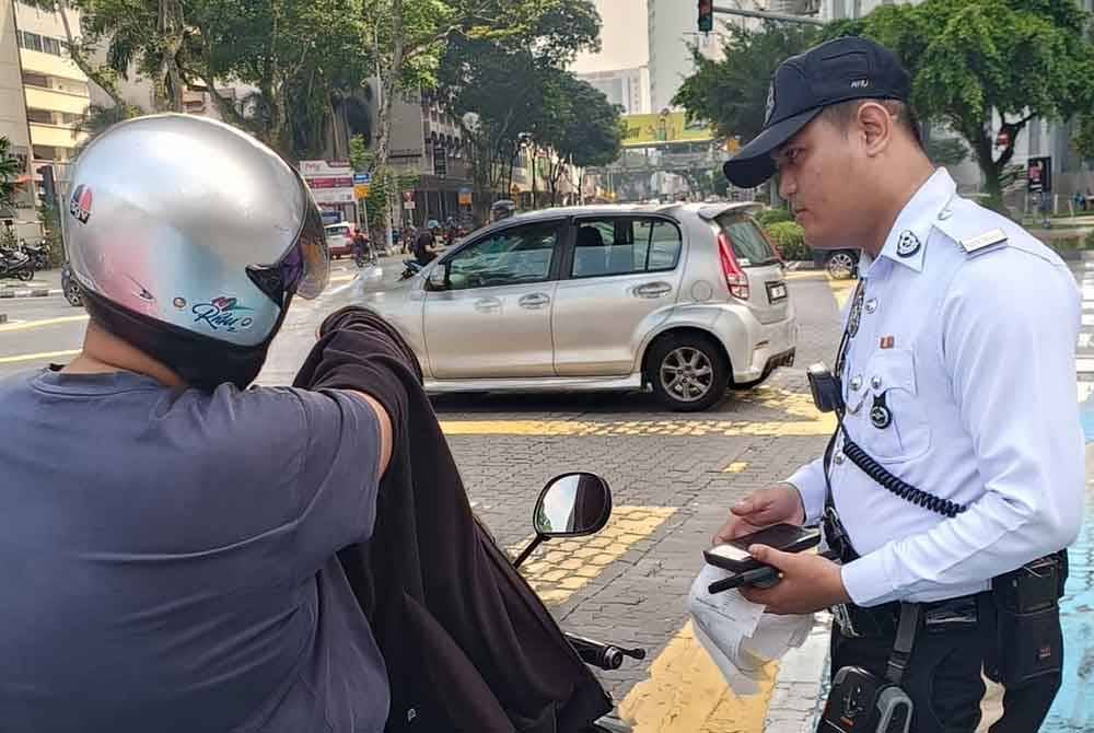 Seorang anggota polis melalukan pemeriksaan ke atas penunggang motosikal menerusi Operasi Hormat Undang-undang Jalan Raya (Op HUU) di Kuala Lumpur pada Selasa. Foto PDRM