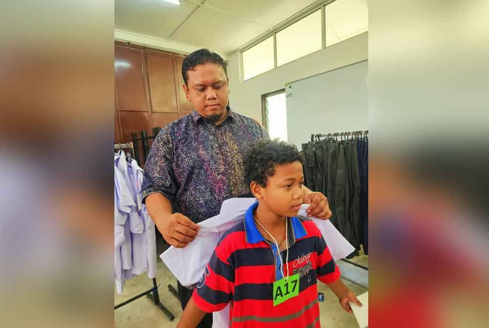 Muhammad Hamzah menyantuni seorang murid sempena program kembali ke sekolah yang diadakan di Kampung Lalang, Januari lalu.