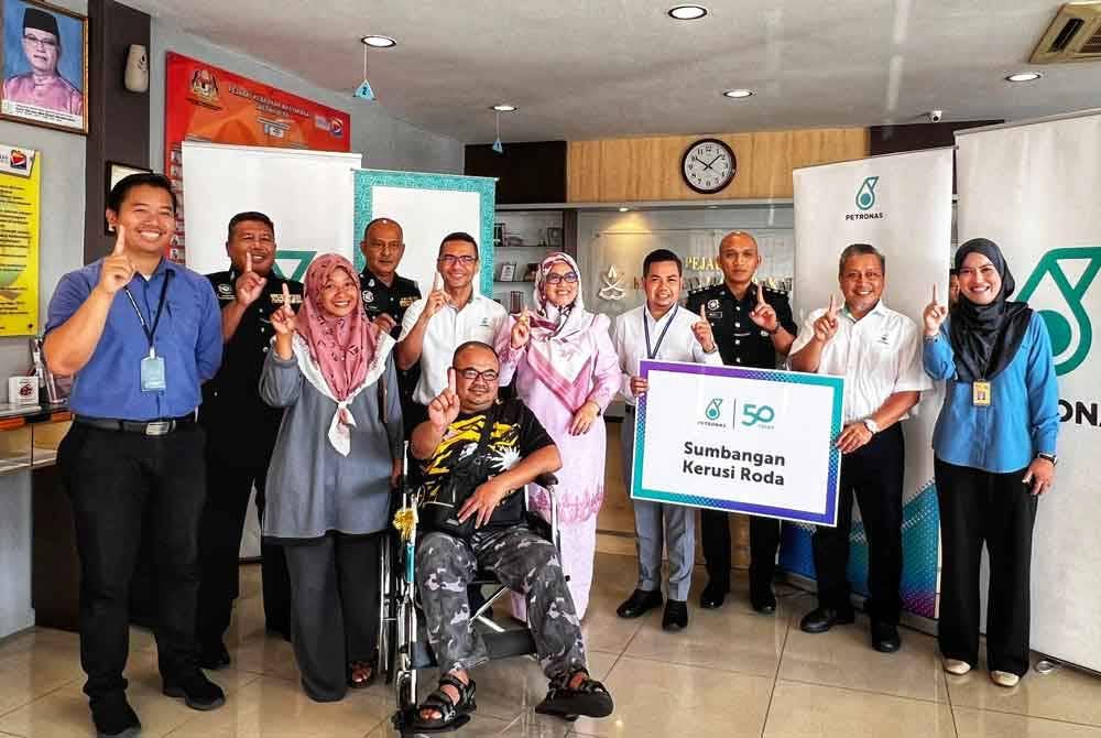 Mohammad Ahmad Shazly (enam dari kanan) dan Sabariah (lima dari kanan) dengan sumbangan kerusi roda yang diterima Azlan bersama Norhadijah (tiga dari kiri).