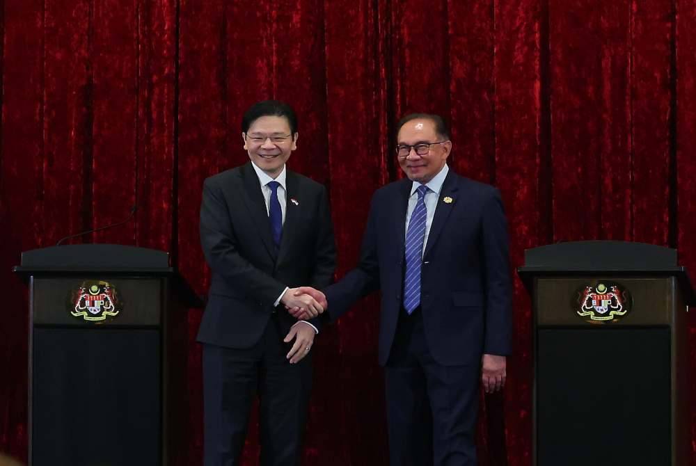 Lawrence (kiri) berjabat tangan dengan Anwar selepas sidang media, pada Rabu. Foto Bernama