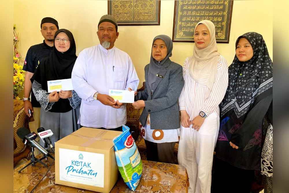 Zakaria (tiga, kiri) semasa menerima kunjungan daripada PERKESO yang diketuai oleh Nora (tiga, kanan) di Kampung Lubuk Tembusu, Kubang Telaga di Bachoki, pada Khamis.