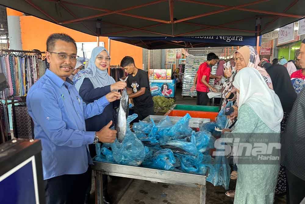 Abdul Rashid (kiri) dan Wan Faizatul Aniza (dua dari kiri) menunjukkan ikan tongkol yang dijual lebih murah di Jualan Khas Semarak Aidiladha.