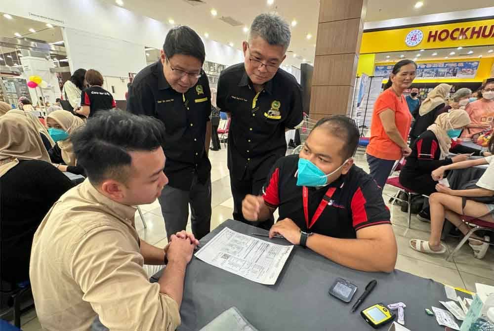 Cherk Yee (berdiri, kiri) mendengar taklimat berkenaan penjagaan kesihatan sempena program Healthier Malaysian Better Malaysia di AEON Mall Kulaijaya, Kulai pada Sabtu.
