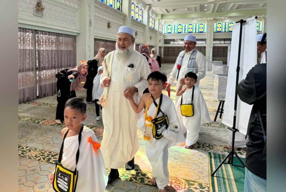Roslan (kiri) turut sama membantu kanak-kanak yang terlibat 'menunaikan haji' sempena Program Simulasi Haji Cilik 2024 di Masjid Sultan Idris Shah II di sini pada Khamis.