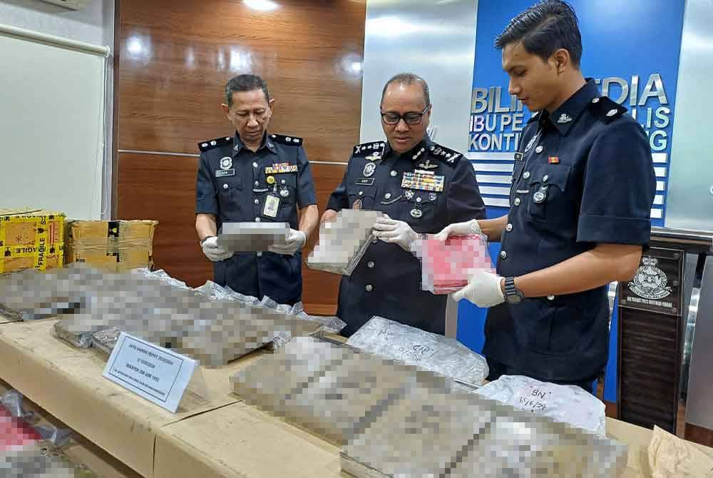 Noor Hisam (tengah) memeriksa bungkus dadah ganja.