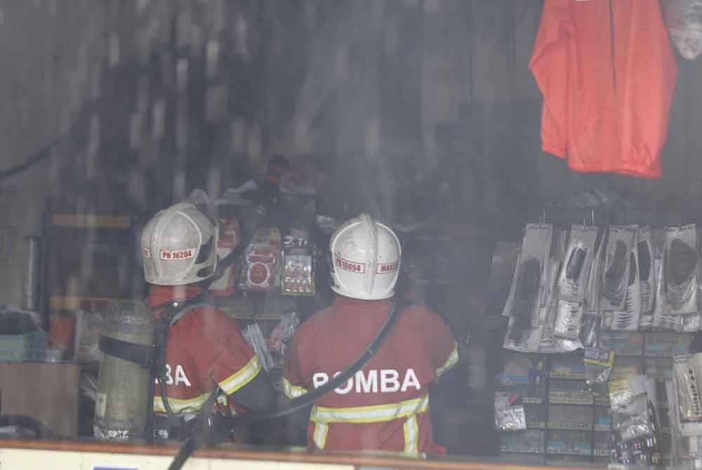Bomba memeriksa kedai milik Danny yang turut terbakar.