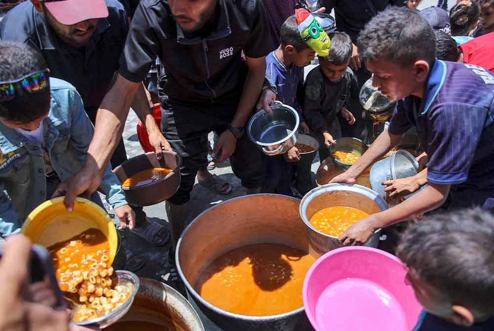 Kanak-kanak beratur untuk mendapatkan makanan diagihkan sekolah UNRWA di kem Jabalia, utara Gaza.