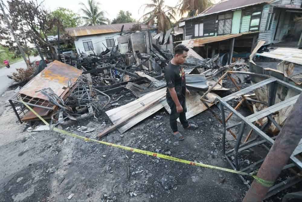 Mohd Zamri Ismail melihat kesan bengkel motosikal miliknya yang terbakar di Kampung Bukit Rangin di sini.