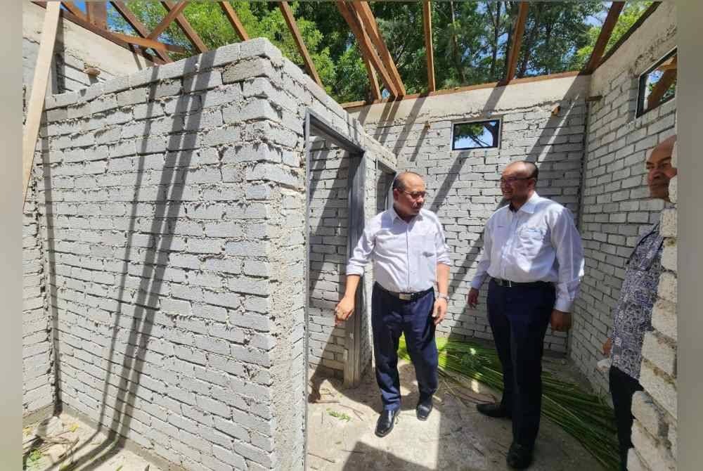 Ahmad Amzad (kiri) bersama Muhtar meninjau proses menaik taraf surau awam di Pantai Batu Buruk di Kuala Terengganu.
