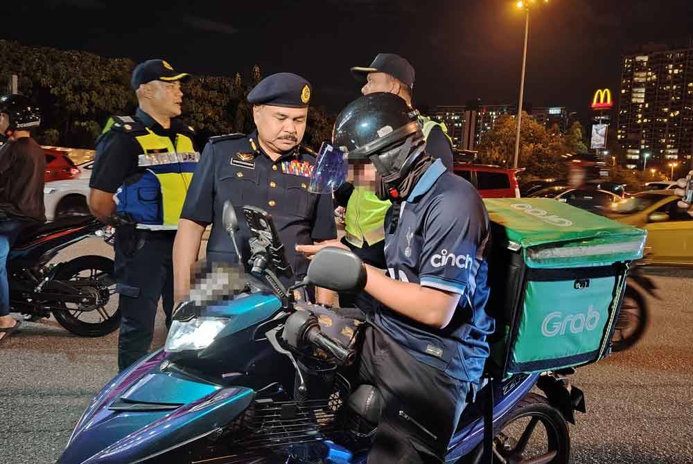Ahmad Kamarunzaman memeriksa penunggang motosikal semasa sekatan jalan raya Op HRAA 2024 di Plaza Tol Petaling Jaya Selatan 5, pada Khamis.