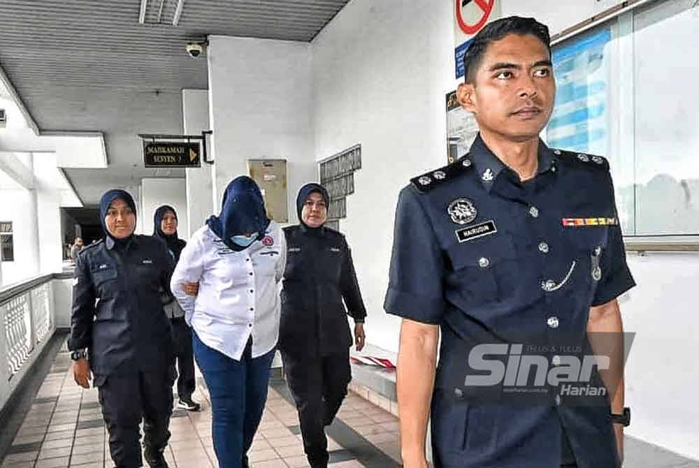 Norhana (tengah) ketika dibawa keluar dari Mahkamah Sesyen Melaka pada Jumaat.