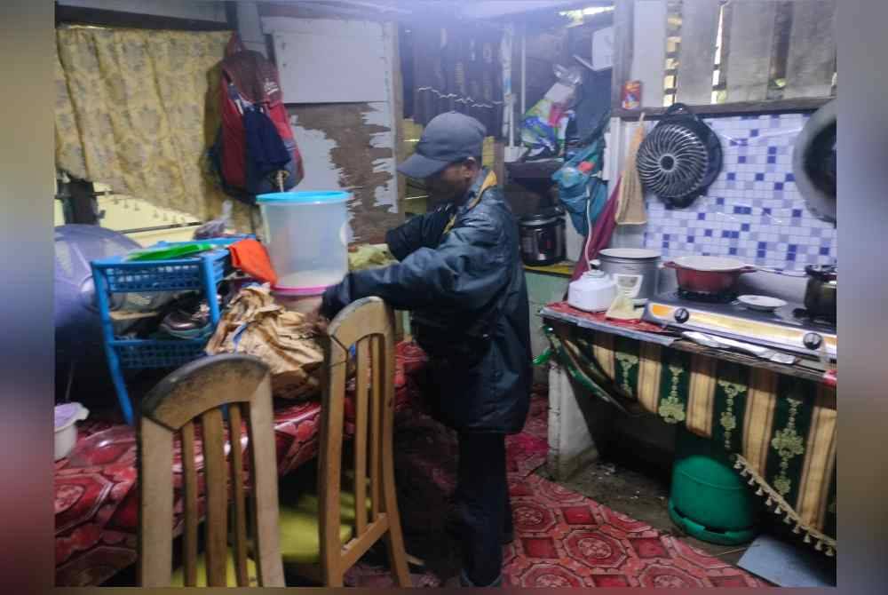 Abd Rashid mengemas peralatan rumah selepas banjir mula surut pada pagi Sabtu.