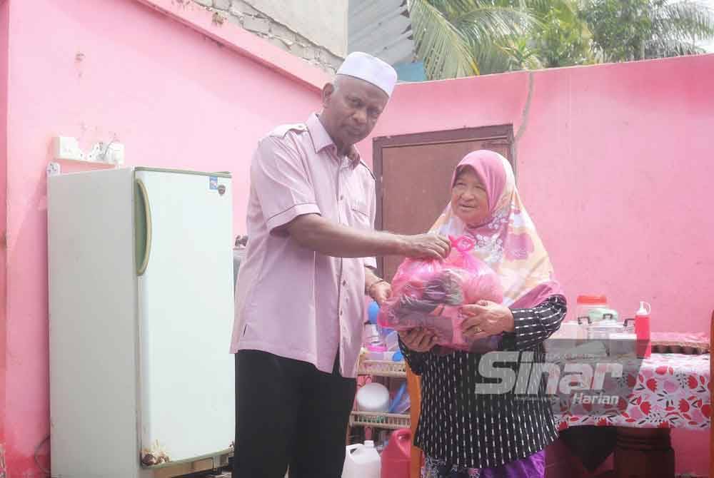 Zainol Abidin menyampaikan sumbangan barangan keperluan kepada Rokiah di rumahnya di Kampung Changhai pada Ahad.