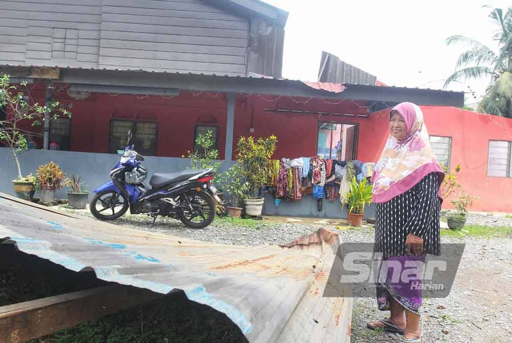 Rokiah menunjukkan sebahagian bumbung rumahnya yang diterbangkan angin.