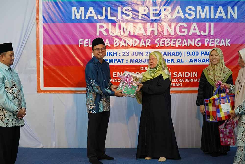 Rosni (dua dari kiri) menerima cenderahati daripada Normah Hanum selepas menyempurnakan Majlis Perasmian Rumah Ngaji Felcra Bandar Seberang Perak di Masjid Jamek Al-Ansar di sini pada Ahad.