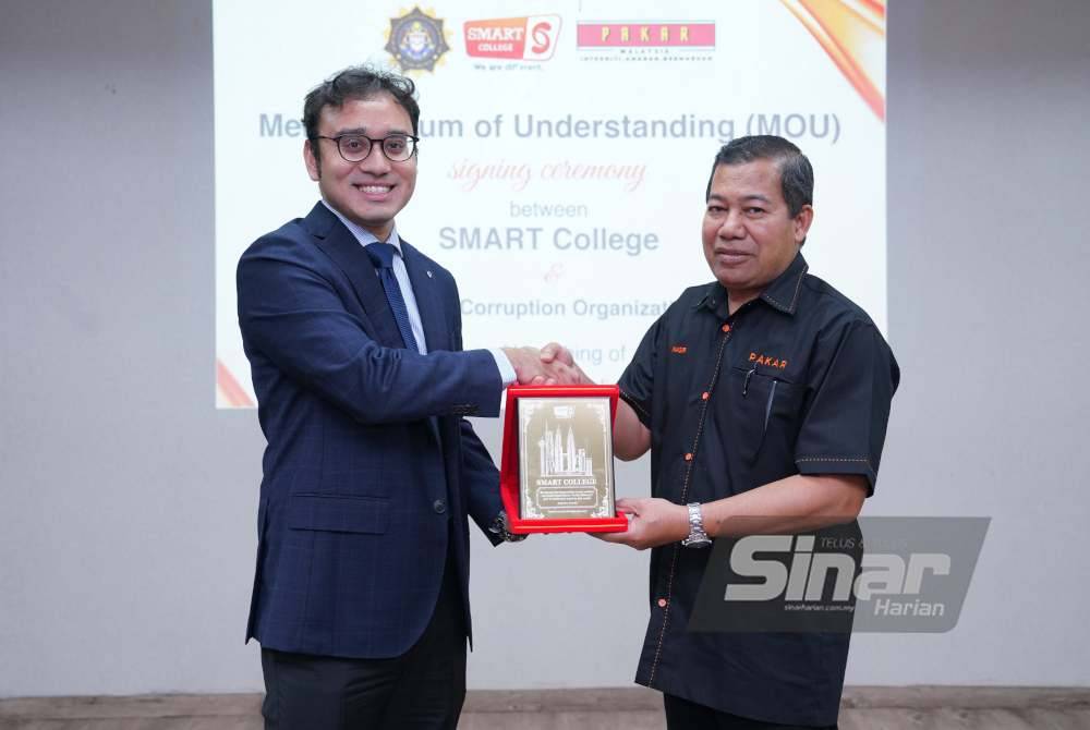 Alexander menyampai cenderati kepada Mohd Nasir. Foto MOHD HALIM ABDUL WAHID