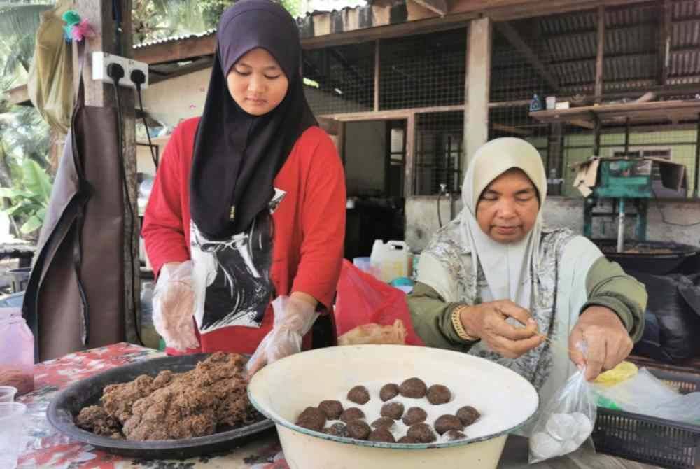 Suri (kanan) dan Nur Damia Arisya menyiapkan kuih tradisional lok lik.