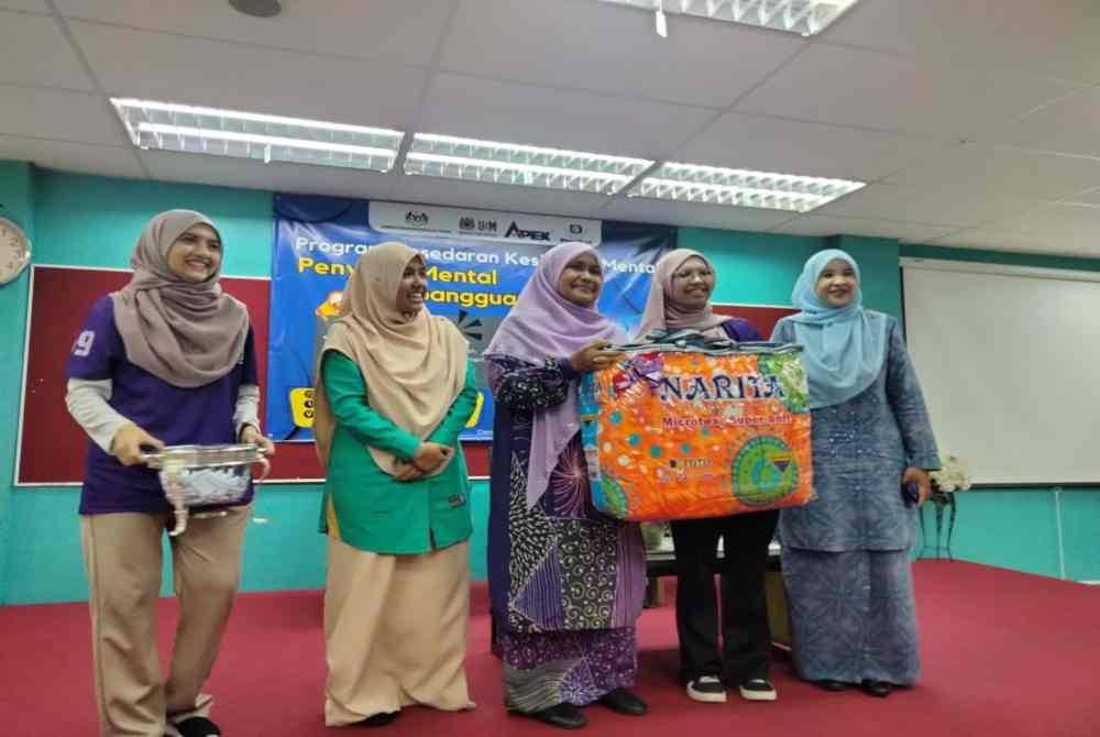 Dr Hafidzah (tengah) menyampaikan hadiah kepada peserta cabutan bertuah sempena Program Kesedaran Kesihatan Mental: Penyakit Mental VS Gangguan Jin?