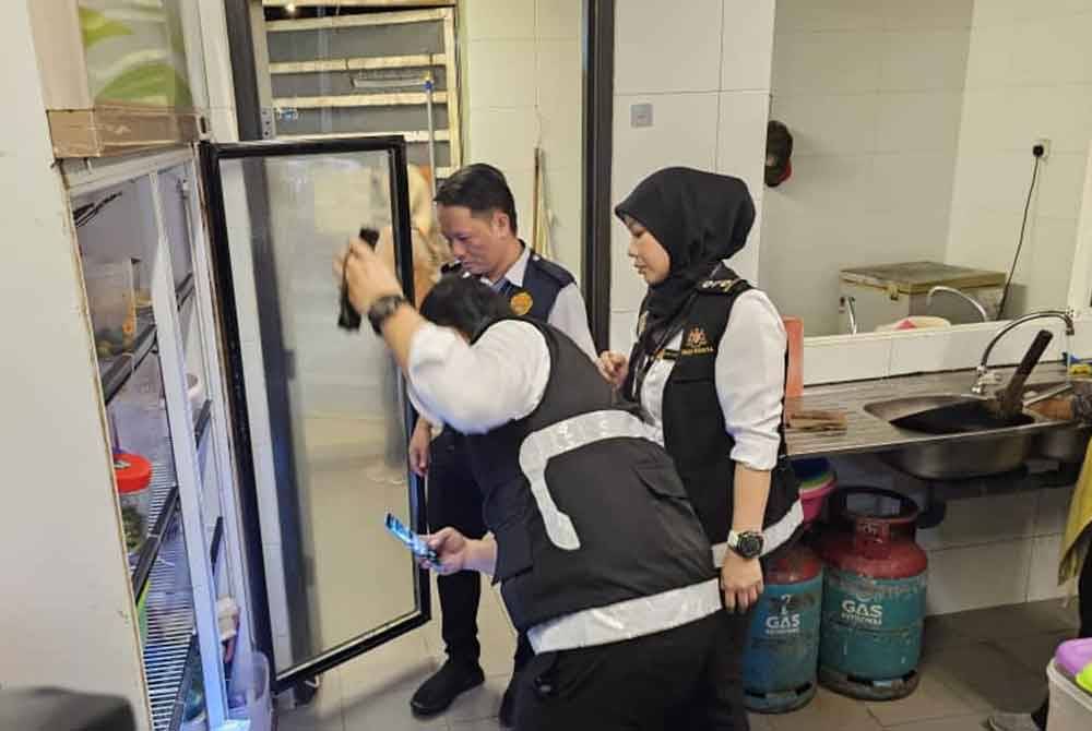 Penguat kuasa PKK Kota Kinabalu memeriksa peti sejuk salah sebuah premis yang diarah tutup dalam operasi yang dijalankan di Anjung Selera, Likas, Kota Kinabalu.