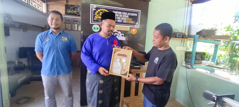 Manndzri (tengah) menerima cenderahati khas daripada usahawan bantuan RISDA, Mohd Rizal semasa mengadakan lawatan kerja di Sik, Kedah.