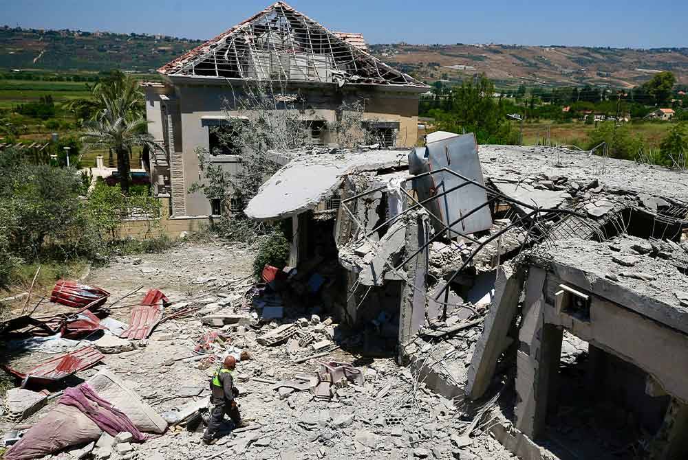 Anggota pertahanan awam Lubnan memerikan kawasan yang menjadi serangan tentera Israel di kampung Khiam, berhampiran sempadan Lubnan. - AFP