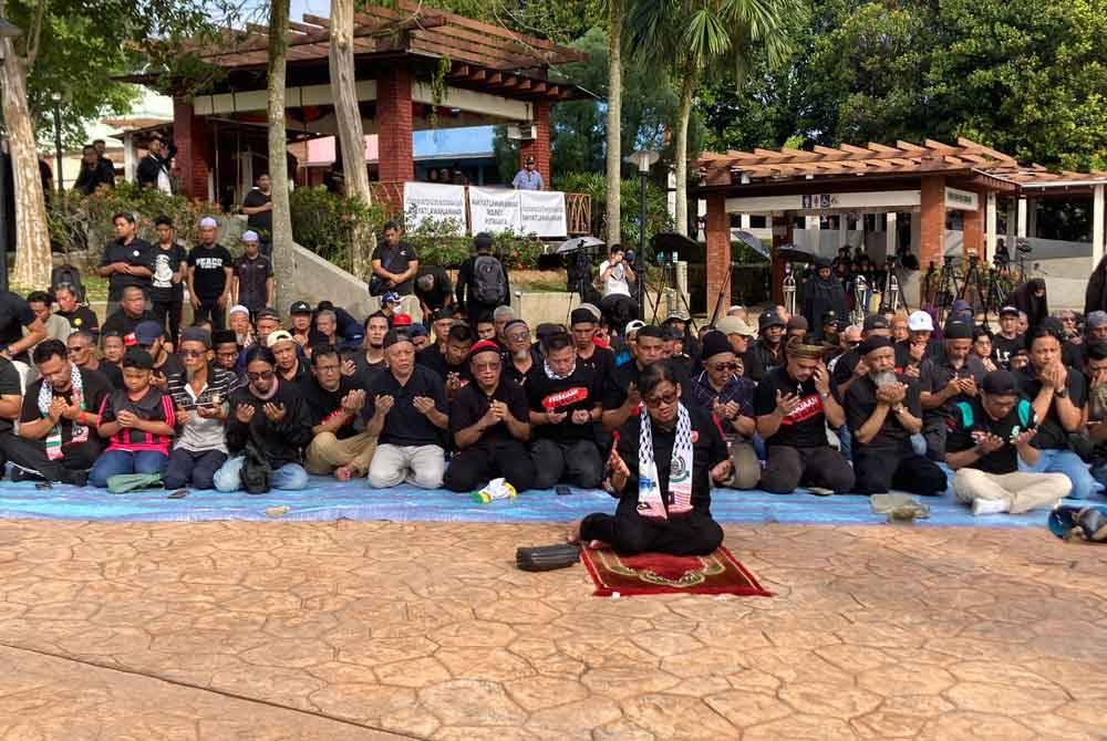 Kumpulan berbaju hitam membaca berdoa selepas menyelesaikan solat asar secara berjemaah sebelum memulakan Perhimpunan Demo Rakyat Lawan Anwar di tempat letak kenderaan Kompleks Seri Perdana, Putrajaya pada Sabtu.
