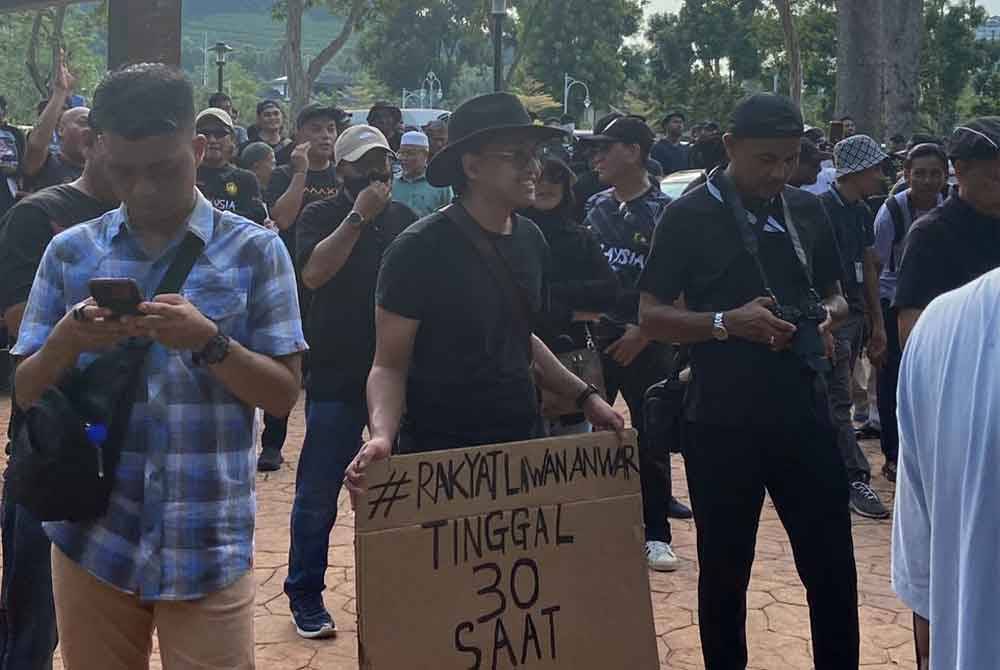Kumpulan baju hitam berkumpul di tempat letak kenderaan di Kompleks Seri Perdana untuk menyertai perhimpunan 'Demo Rakyat Lawan Anwar' pada Sabtu.