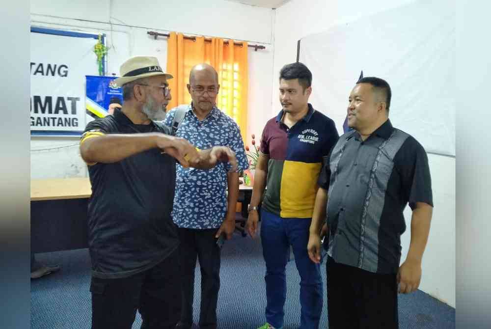 Syed Abu Hussin (kiri) berbincang sesuatu dengan pegawainya selepas sidang akhbar di Pusat Khidmat Ahli Parlimen Bukit Gantang pada Ahad.