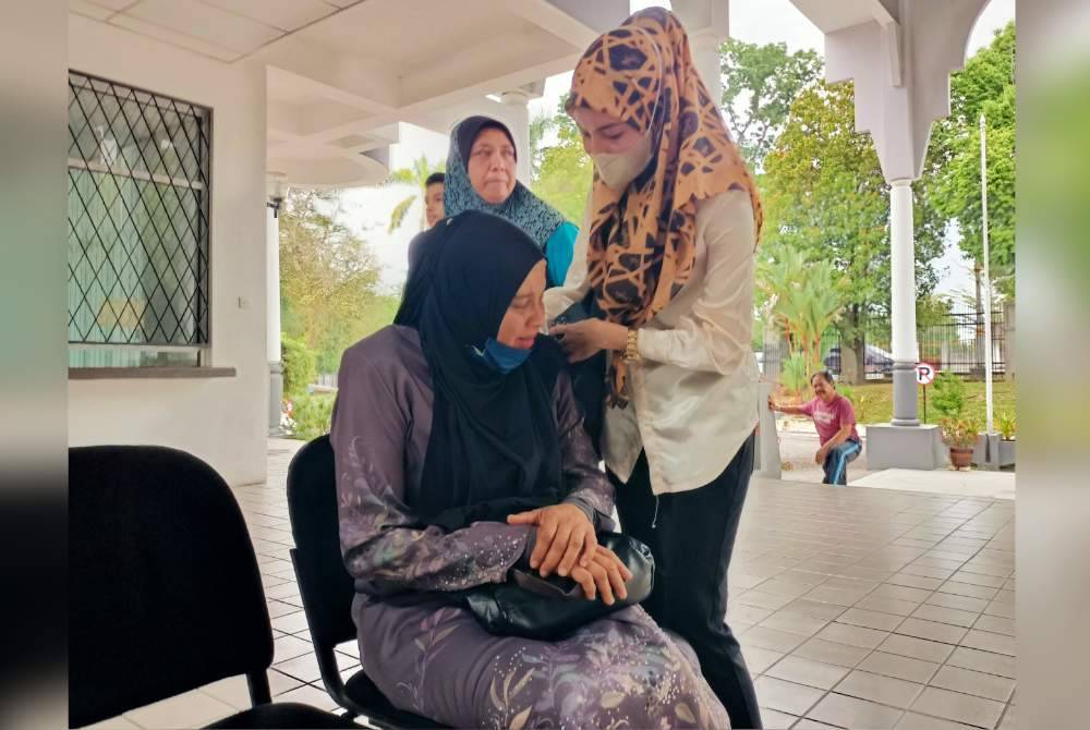 Rozita ditenangkan ahli keluarga ketika hadir ke Mahkamah Majistret Batu Gajah pada Isnin.