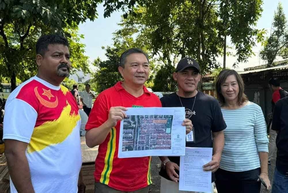Sze Han (dua dari kiri) menunjukkan pelan tebatan banjir di Taman Kinrara 2 di sini.