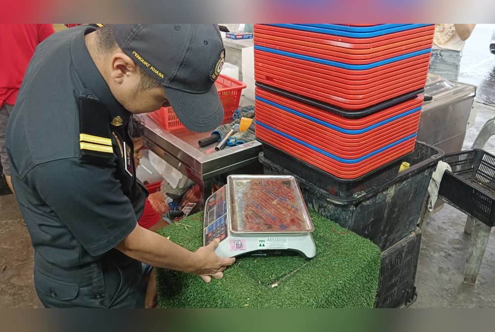 Anggota KPDN Johor memeriksa alat timbang di premis menjual durian, pada Ahad.